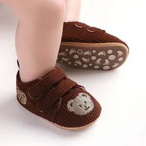 Nahaufnahme brauner Baby-Lauflernschuhe aus Cord mit Bärenstickerei und rutschfester Sohle
