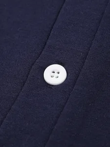 Dettaglio di un bottone bianco a quattro fori sul tessuto di una polo in maglia blu scuro