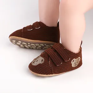 Nahaufnahme brauner Cord-Lauflernschuhe für Babys mit niedlicher Bärenstickerei