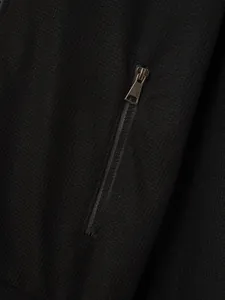 Macro detail of men's black waffle knit jacket featuring a sleek metal zipper pocket design
