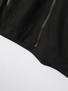 Close-up detail of black waffle-knit jacket showing metal zipper and textured fabric finish.