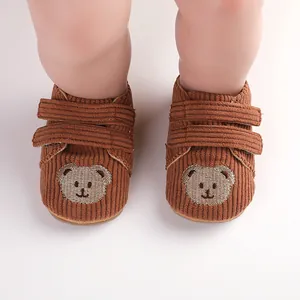 Detaillierte Nahaufnahme von braunen Cord-Lauflernschuhen mit süßer Bärenstickerei
