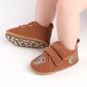 Braune Lauflernschuhe aus Cord mit Bärenstickerei und rutschfester Sohle für Babys.