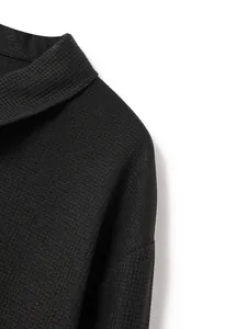 Detailed macro shot of high-quality black waffle knit fabric on a men's lapel cardigan