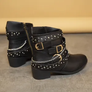 Vista detallada de botas Martin negras con tachuelas plateadas, hebillas y cadenas.
