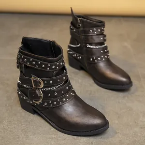 Detalle de botines marrones de estilo occidental con hebillas y remaches metálicos