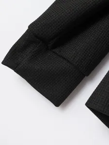 Close-up detail of premium black waffle knit fabric and ribbed cuff on a men's zip jacket