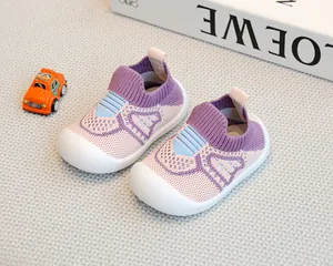 Detailed view of purple fly-knit baby shoes on a textured mat with toys.