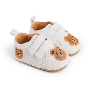 Close-up of off-white corduroy baby walker shoes with cute embroidered bear patches.