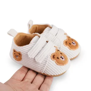 Detailed view of white corduroy baby walker shoes featuring cute brown bear embroidery