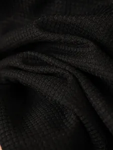 Detailed macro shot showing the high-quality black waffle knit texture of a men's autumn jacket.