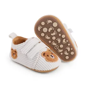 Close-up of white corduroy baby walking shoes featuring anti-slip sole and cute bear design
