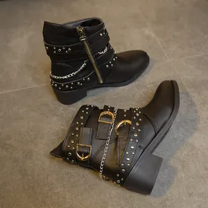 Primer plano de botas Martin negras estilo punk con hebillas doradas y cadenas de plata