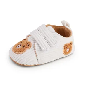 Detailed view of white corduroy baby walking shoes featuring cute brown bear embroidery