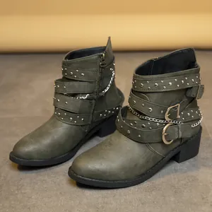 Detalle lateral de botines Martin verde oliva con hebillas, tachuelas y cadenas plata.