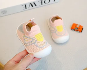 Close-up of pink knitted baby walking shoes with soft non-slip white rubber soles