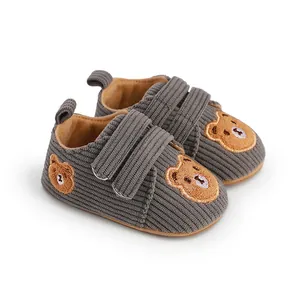 Close-up of grey corduroy baby walking shoes featuring cute bear embroidery and velcro straps