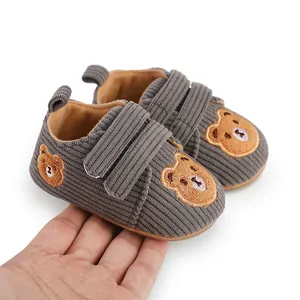 Detailed view of gray corduroy baby shoes with cute bear embroidery and velcro straps