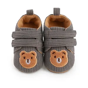 Detailed view of grey corduroy baby walking shoes with bear embroidery and velcro straps.