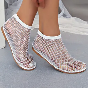 Primer plano de sandalias blancas de rejilla con brillantes pedrería en los pies