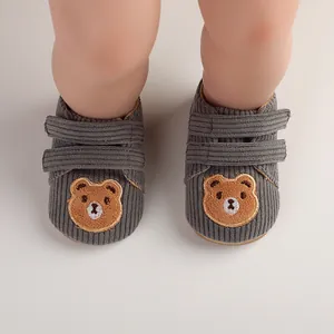 Close-up of grey corduroy baby walking shoes featuring cute bear embroidery detail