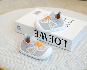 Grey breathable fly-knit baby sock shoes with orange accents displayed on a white book