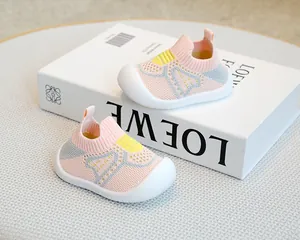 Pink knit baby sock shoes with soft non-slip sole displayed on a white book