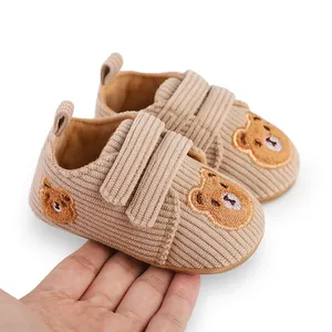 Detailed view of beige corduroy baby walking shoes with cute embroidered bear design