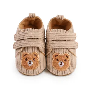 Close-up front view of beige corduroy baby walker shoes with cute bear embroidery detail