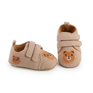 Close-up of beige corduroy baby walking shoes featuring a cute cartoon bear embroidery patch.