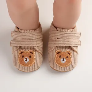 Detailed view of beige corduroy baby walker shoes with cute bear embroidery.