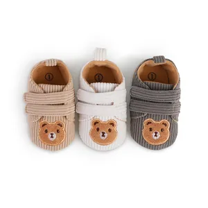 Detailed view of three colors of corduroy baby walking shoes with bear embroidery