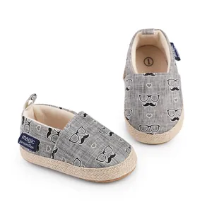 Nahaufnahme grauer Baby-Lauflernschuhe mit Schnurrbart-Print und gewebter Jute-Sohle