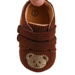 Detailed view of a brown corduroy baby walking shoe with embroidered bear face design