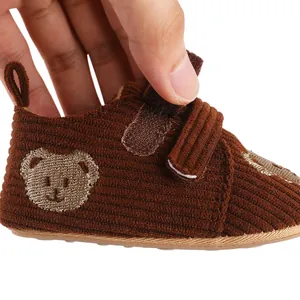 Close-up of the velcro closure on a brown corduroy baby shoe with cute bear detail