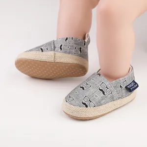 Detailansicht grauer Baby-Lauflernschuhe mit Schnurrbart-Muster und Jutesohlen.
