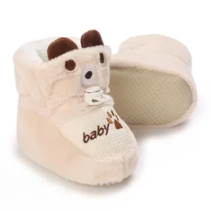 Close-up of cozy plush baby winter boots with anti-slip soles and bear design.