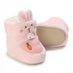 Détail de bottes roses en peluche pour bébé avec broderie carotte et semelle antidérapante.