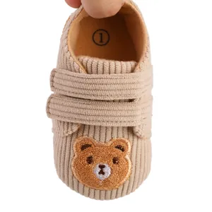 Close-up view of soft khaki corduroy infant shoe featuring cute embroidered bear design