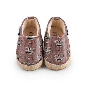 Detailansicht brauner Baby-Lauflernschuhe mit Schnurrbart- und Brillen-Motiv