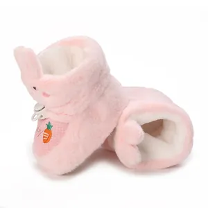 Gros plan de bottines en peluche rose pour bébé avec oreilles de lapin et carotte brodée