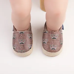 Nahaufnahme von Kleinkindschuhen mit Schnurrbart- und Brillenmuster an Babybeinen