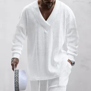 Nahaufnahme eines weißen Strick-V-Ausschnitt-Pullovers mit passender Hose am Model.