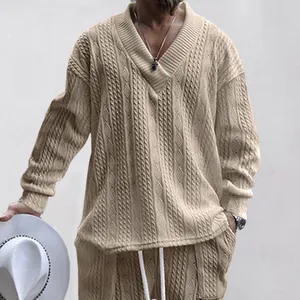 Detail van beige herentrui met V-hals en kabelgebreid patroon met getextureerde jacquard