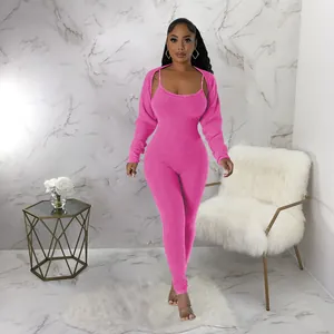 Full-length model view of a pink ribbed knit two-piece jumpsuit and shrug set in a studio.