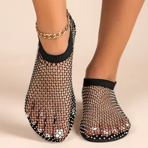 Nahaufnahme von sexy flachen Sandalen mit Strasssteinen und funkelndem Netzdesign.