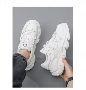 Close-up detail of white leather chunky sneakers with thick wavy sole and green accents