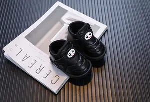 Vue macro de bottes de neige noires pour bébés avec un smiley cartoon et une texture rembourrée