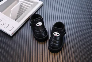 Gros plan de bottes de neige noires pour bébés avec smiley et doublure peluche.