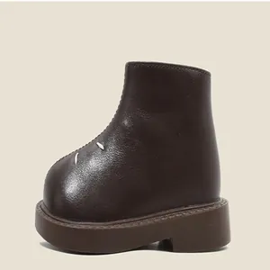 Zoom sur une bottine en cuir marron pour enfant avec bout arrondi et semelle plateforme.